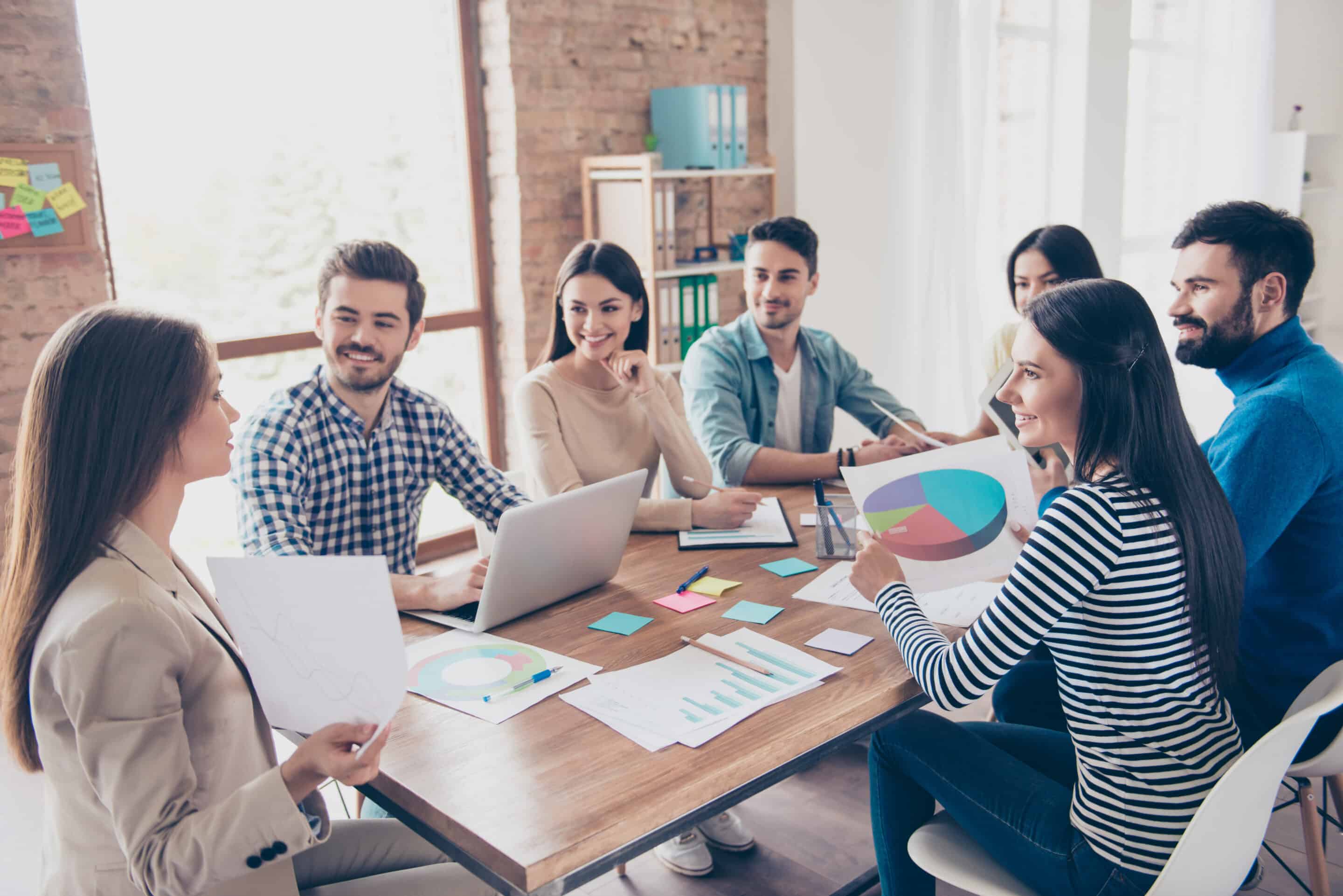 Team building concept. Meeting of colleagues, all of them are in casual clothes, smiling and discussing the company`s development strategy at nice cozy office